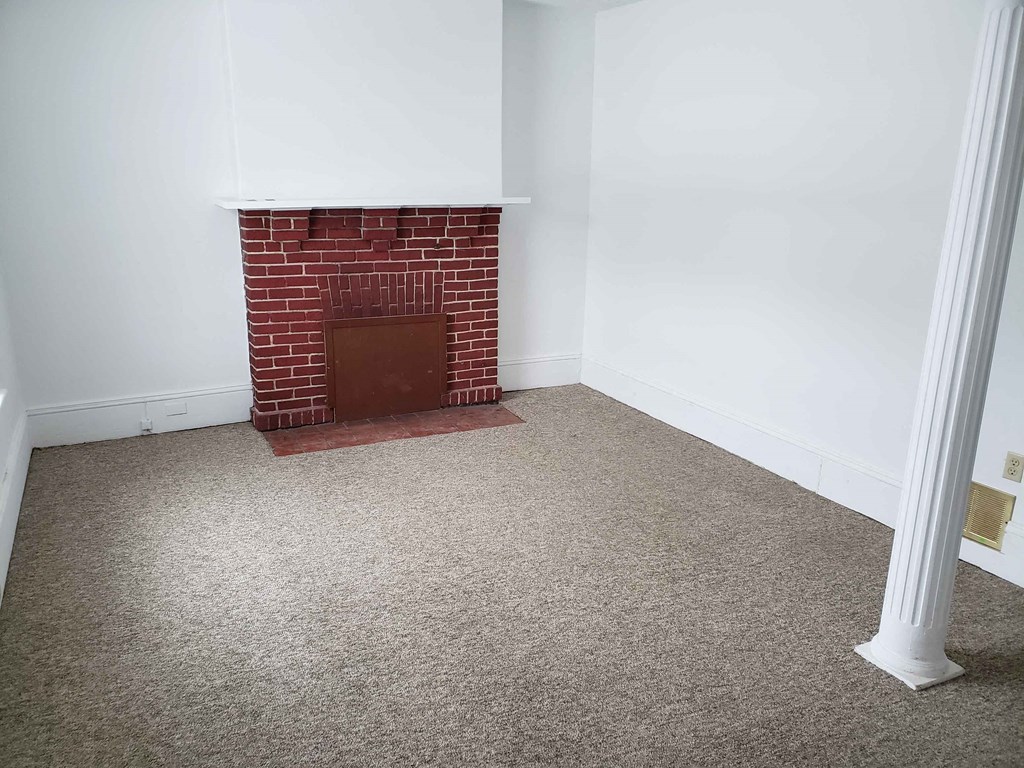 a room with a brick fireplace and a carpeted floor
