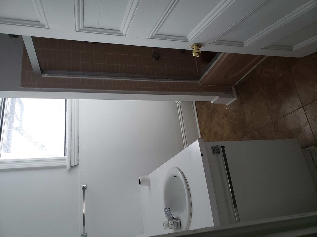 a white bathroom with a urinal and a window