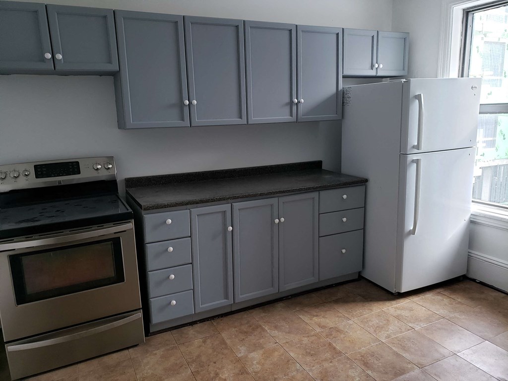 a kitchen with gray cabinets and stainless steel appliances