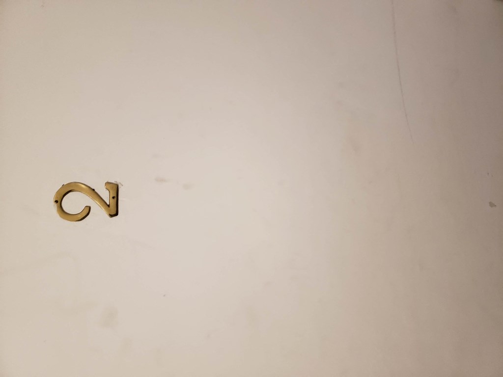 a gold letter c on a white wall