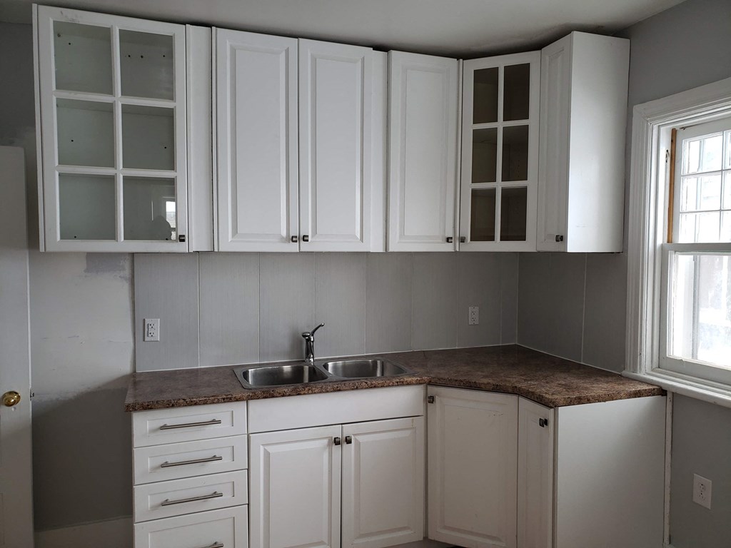 an empty kitchen with white cabinets and a sink