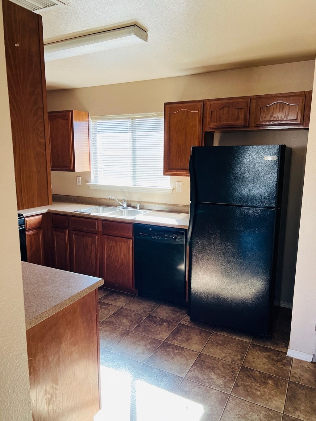 a kitchen with a black refrigerator and wooden cabinets