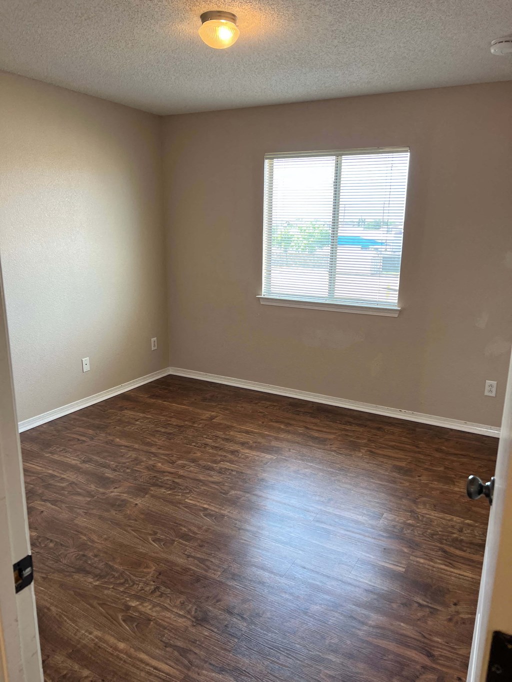 an empty room with wood floors and a window