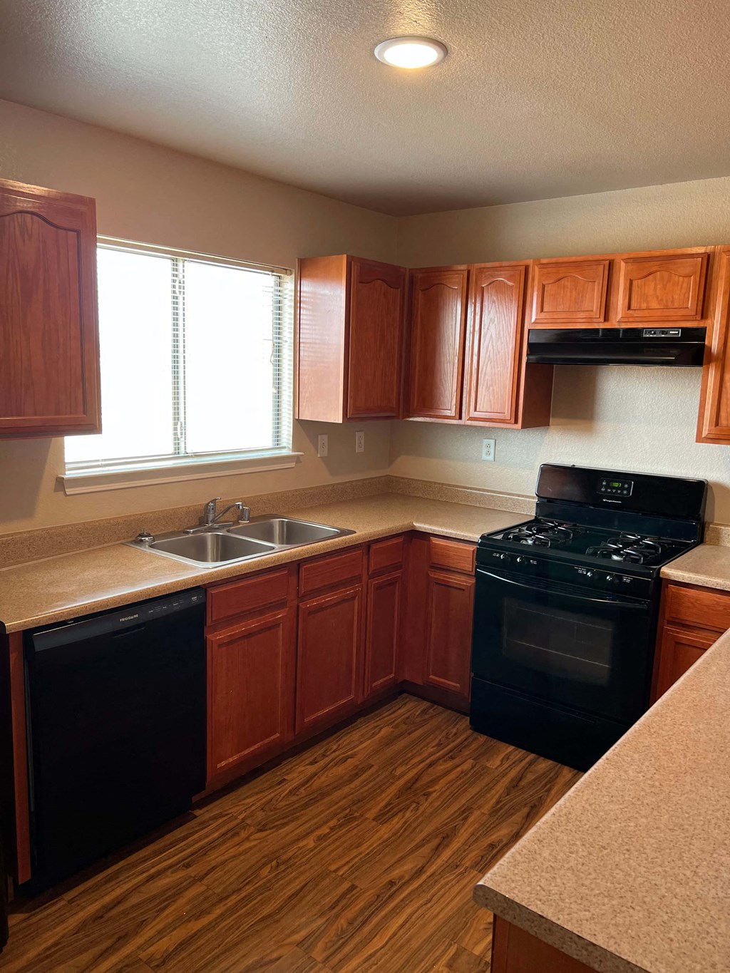 a kitchen with wooden cabinets and a black stove and a sink