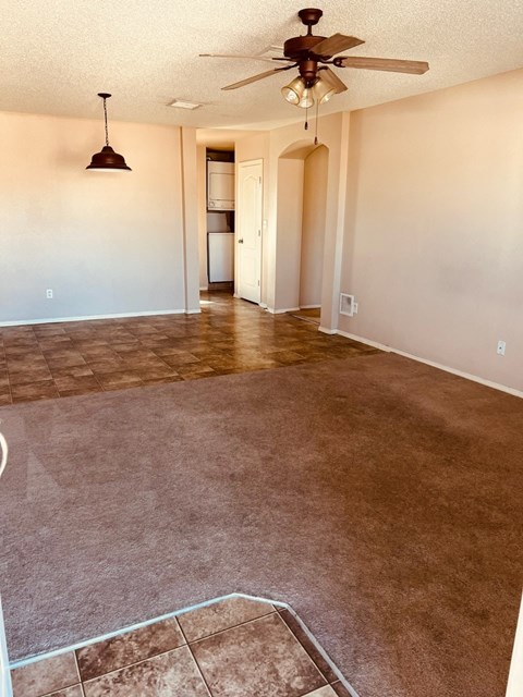 an empty living room with carpet and a ceiling fan