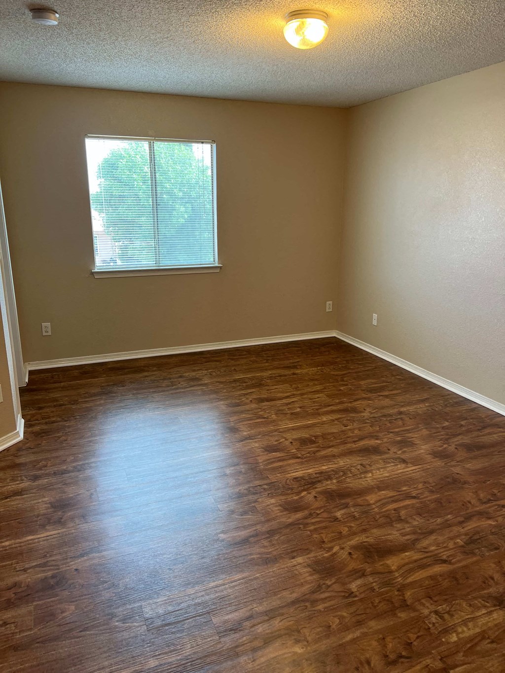 an empty living room with wooden floors and a window