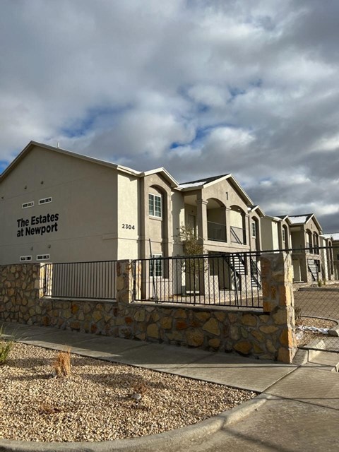a building with a stone wall and a fence in front of it