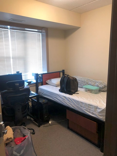A small bedroom with a bed, desk, and chair.