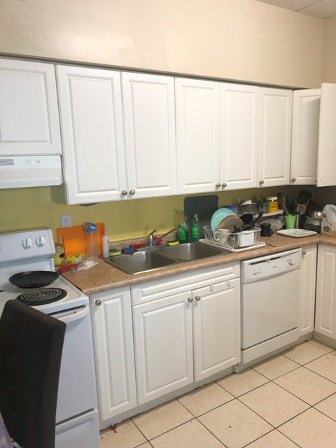 A kitchen with white cabinets and a stove top oven.