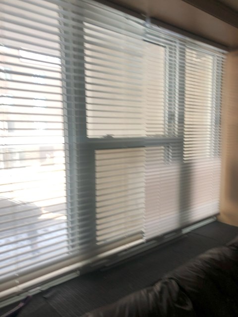 A window with white blinds in a room.
