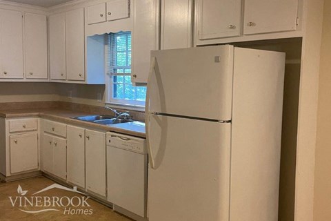 a white kitchen with white cabinets and a white refrigerator