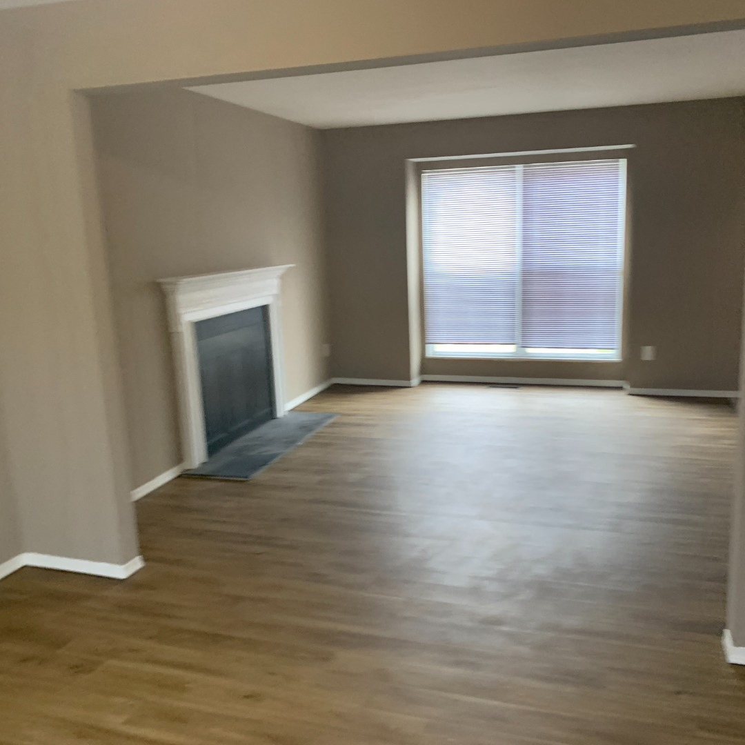 an empty living room with wood floors and a window