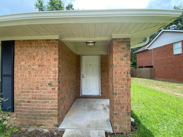 A white door is on the left side of a brick wall.
