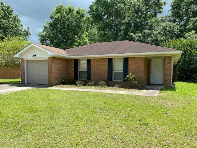 A house with a brown roof and a white door is surrounded by green grass and trees.