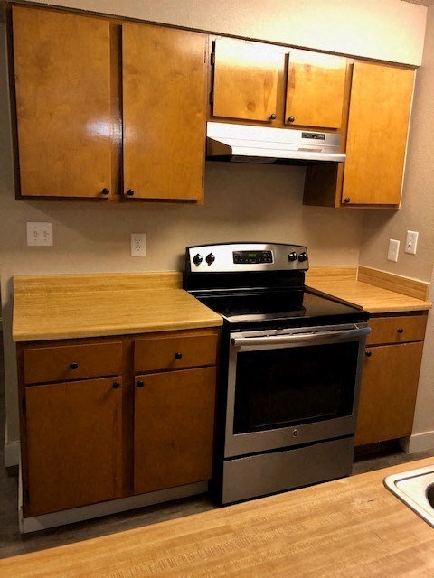 A kitchen with wooden cabinets and a stainless steel oven.
