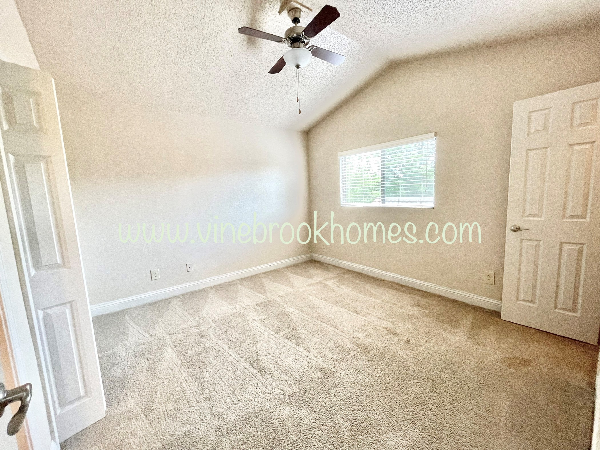 an empty living room with a ceiling fan and a closet