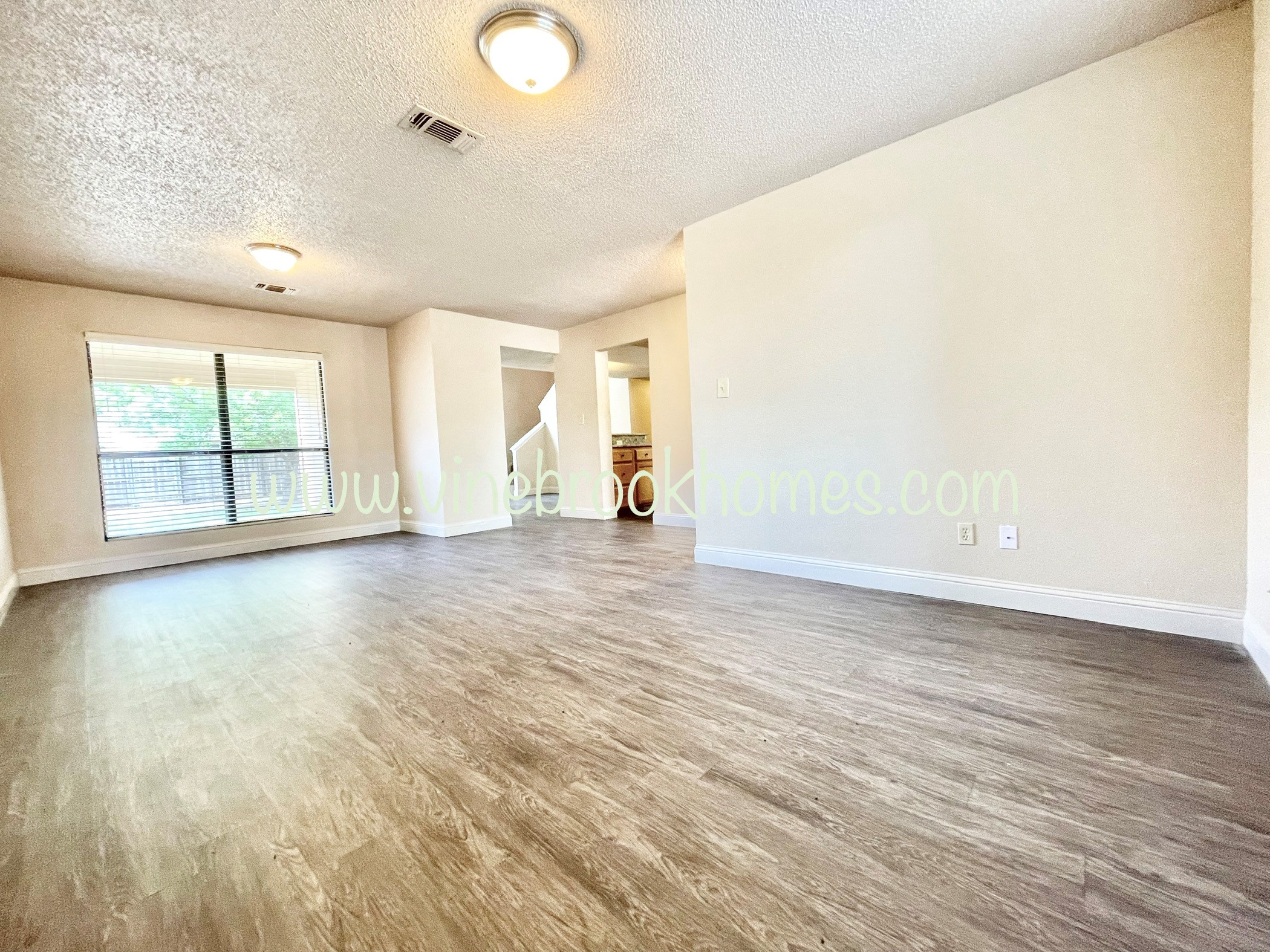 an empty living room with hardwood floors and a large window