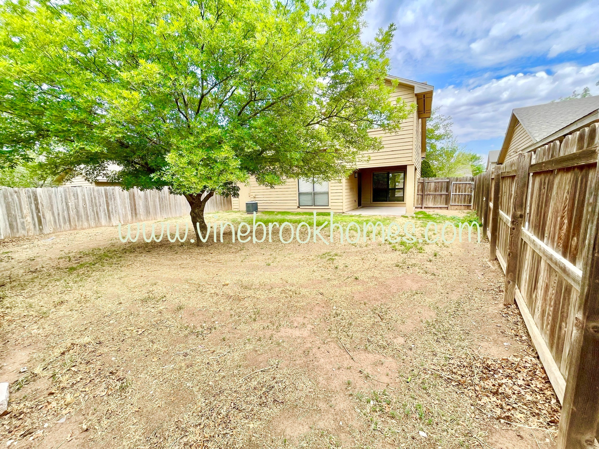 the backyard of a house with a tree and a fence