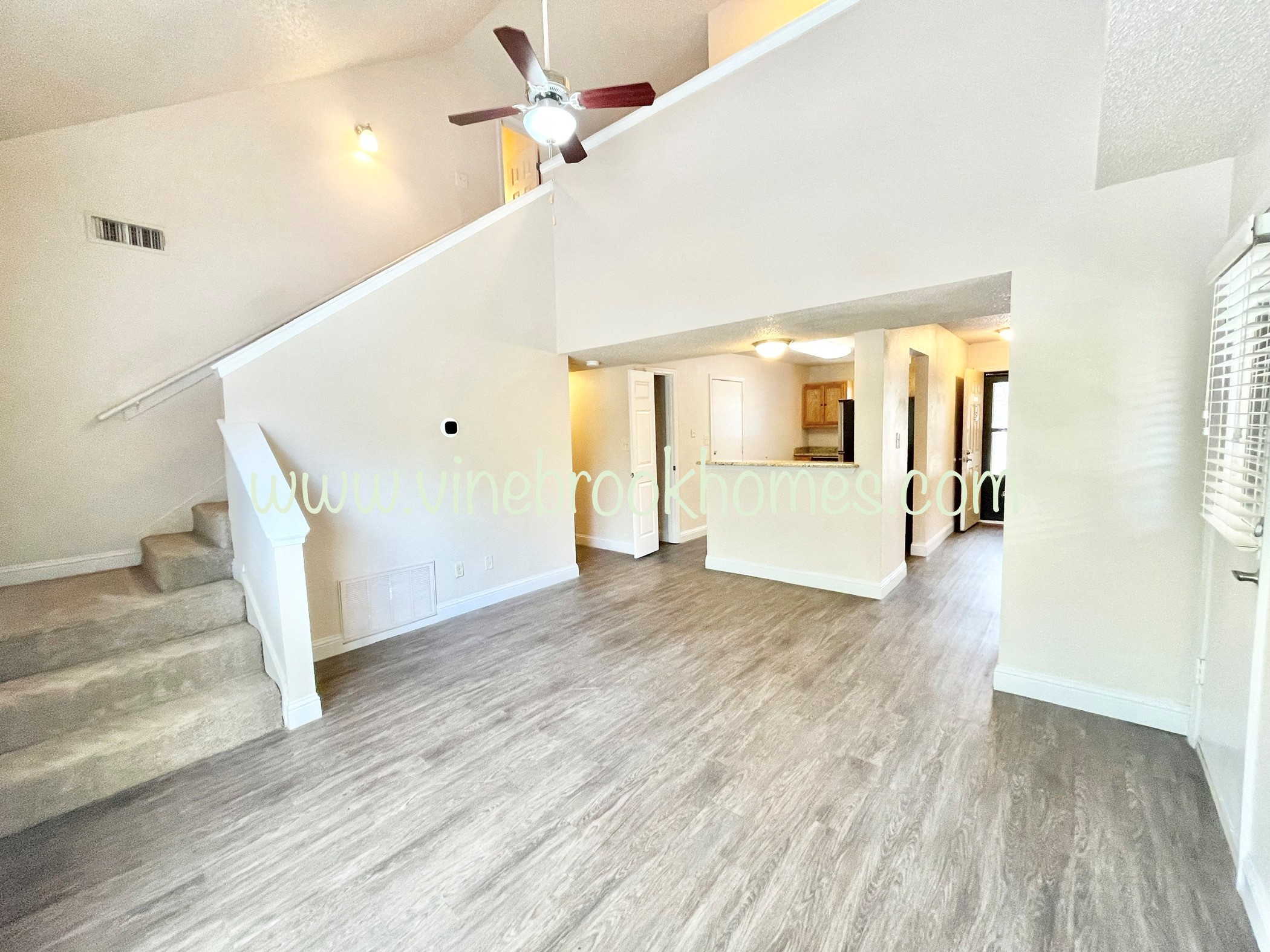 the upstairs living room has a ceiling fan and hardwood floors