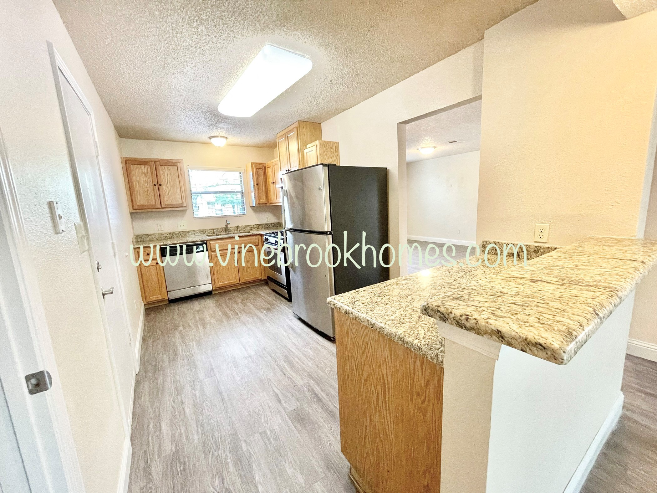 a kitchen with a granite counter top and a stainless steel refrigerator