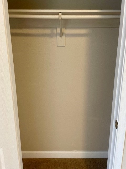 A white closet with a hanger on the rod.