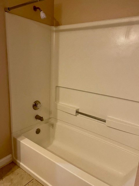 A white bathtub with a shower head and faucet.
