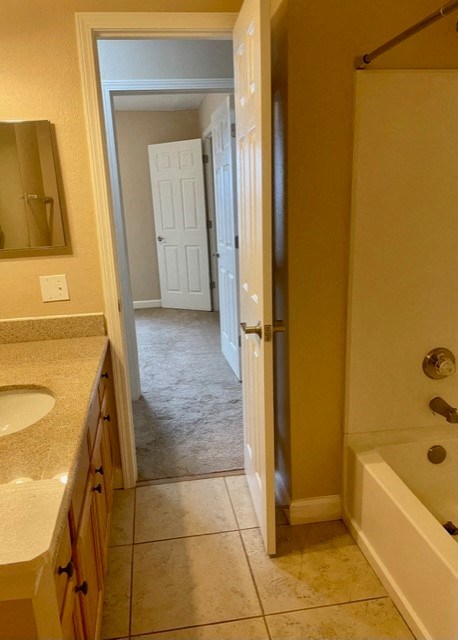 A bathroom with a sink, mirror, and bathtub.