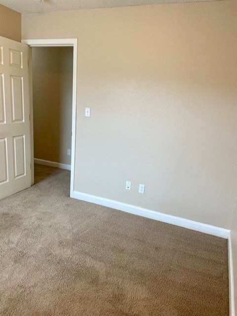 A room with a carpeted floor and a white door.