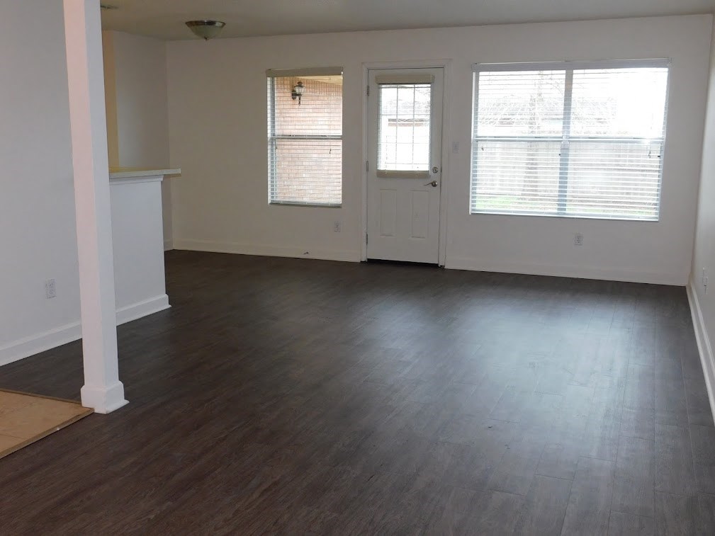 an empty living room with wood floors and a door and window