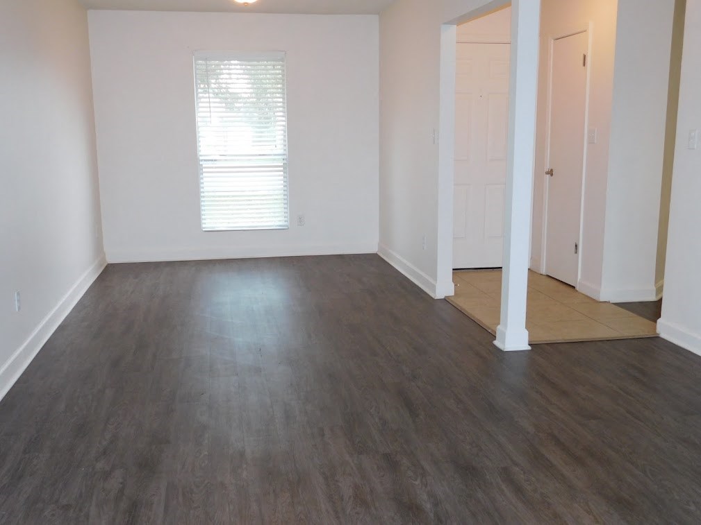 an empty living room with wood floors and white walls