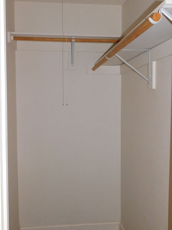 a closet in a room with a white wall and a hanging rack