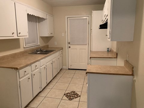 A kitchen with white cabinets and a brown countertop.