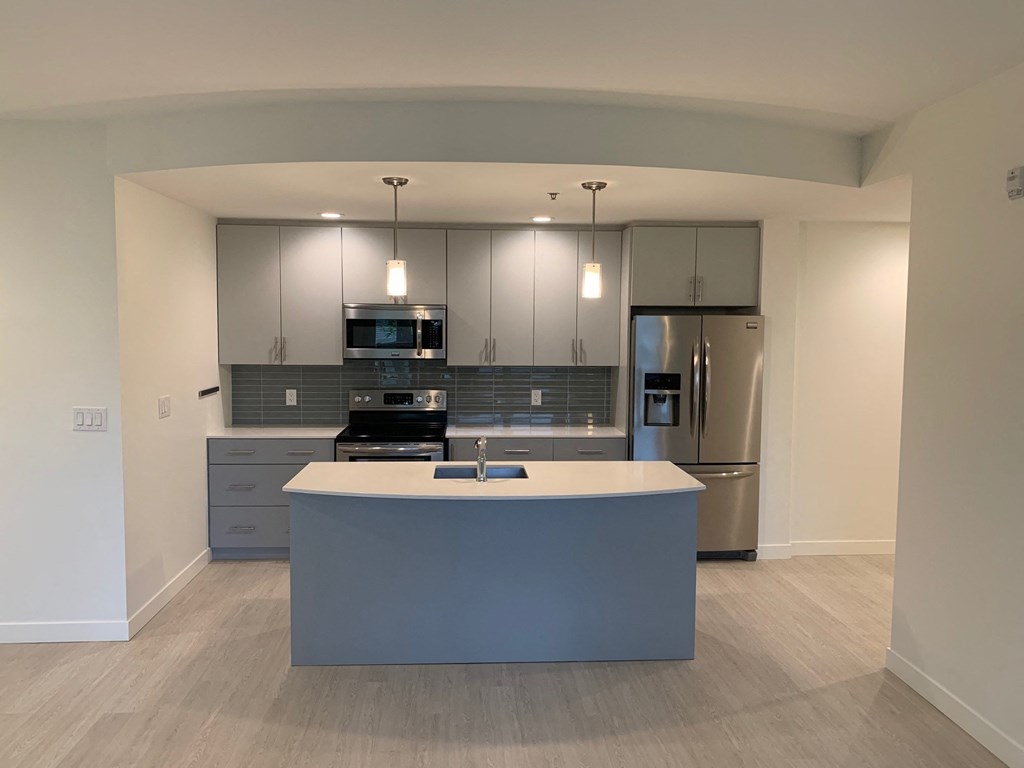 an open kitchen with a blue island and stainless steel appliances
