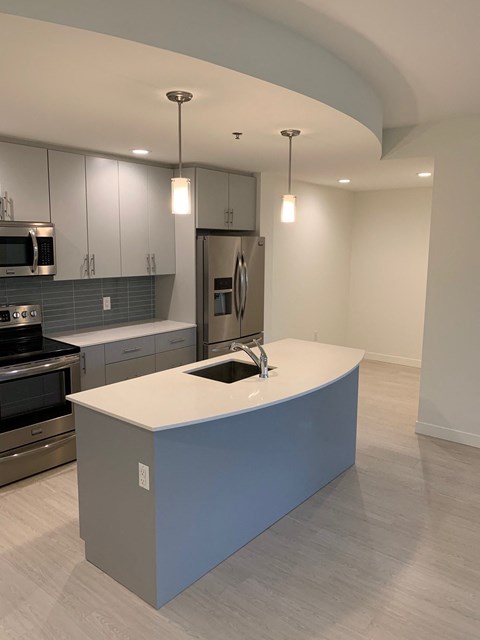 an open kitchen with a blue island and stainless steel appliances