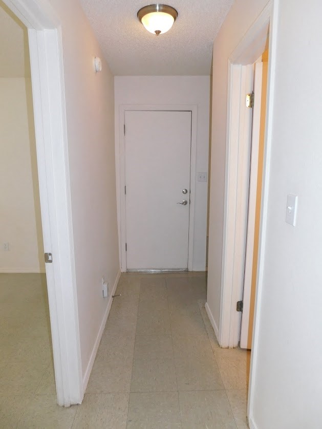 a hallway with a white door and a tile floor