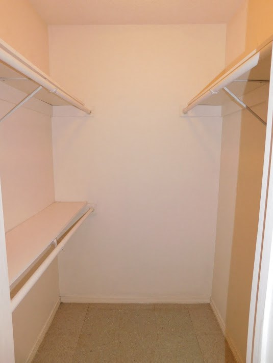 a walk in closet with empty shelves and a white wall