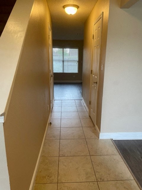 a hallway with a door and a tile floor