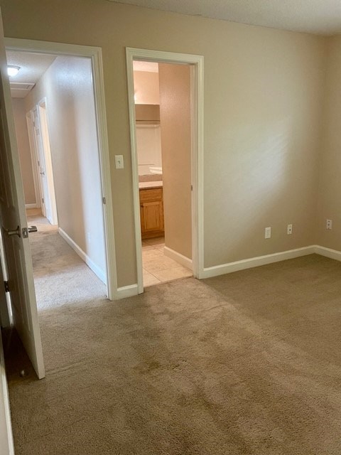 an empty living room with a door open to a bathroom