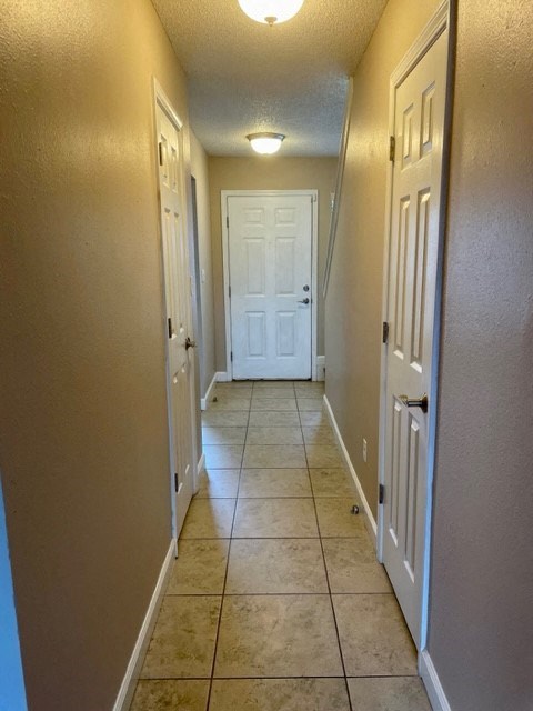 a hallway with a white door and a tile floor