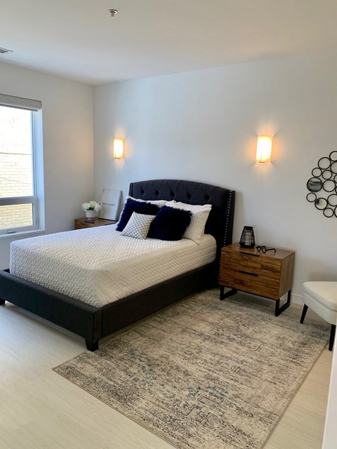 a bedroom with a bed and two nightstands and a window