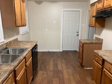 A kitchen with wooden cabinets and a white door.