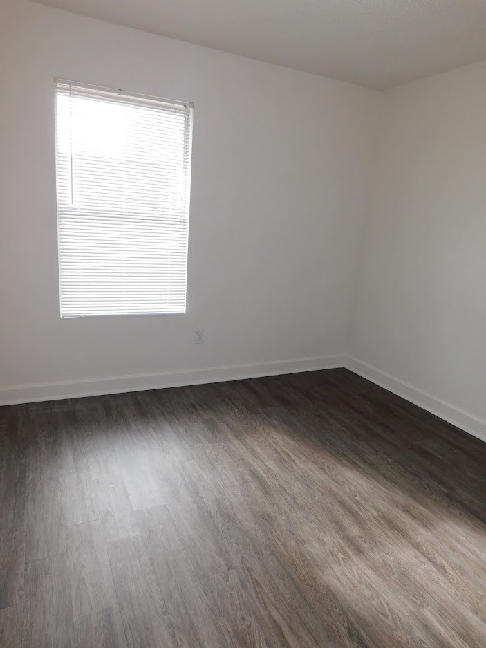A room with a window and wooden flooring.