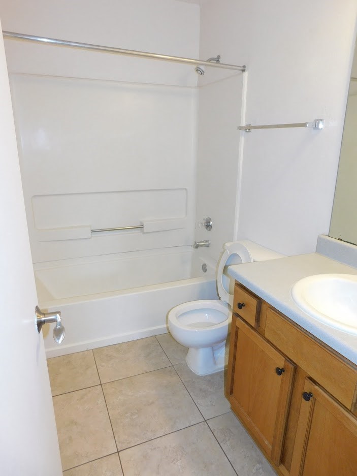 A white toilet in a bathroom with a white tub and a white sink.
