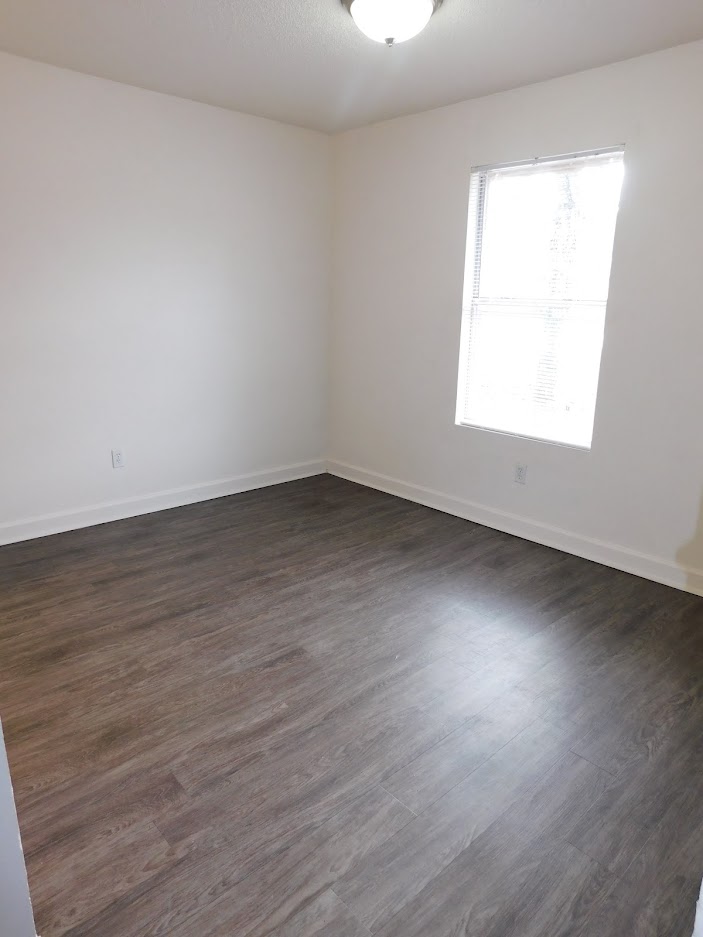A room with a window and wooden flooring.
