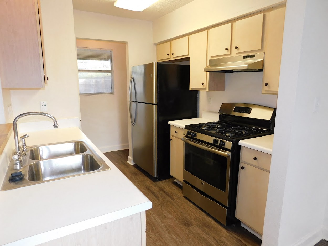 A kitchen with a black fridge, stove, and oven.