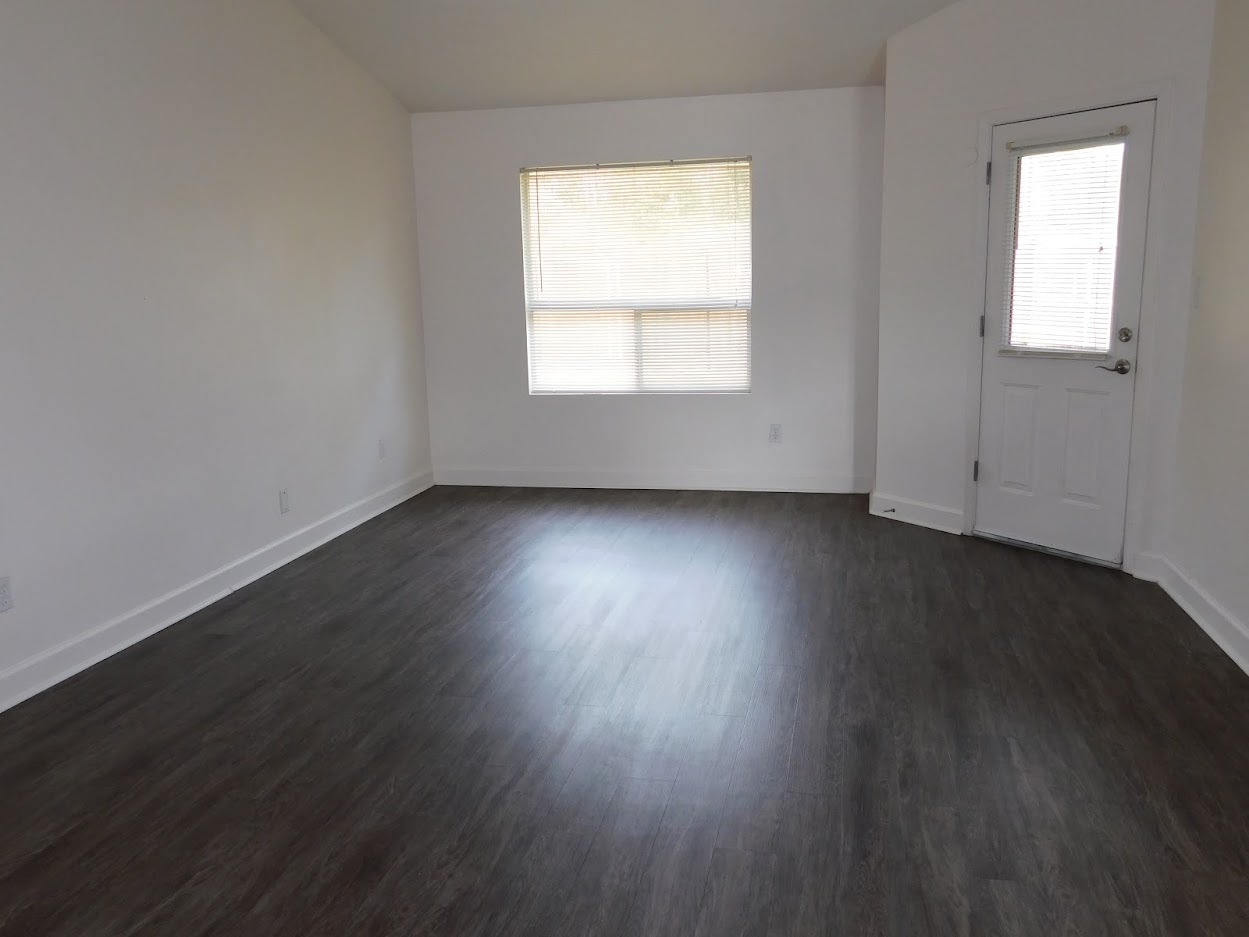 A room with a wooden floor and a window with blinds.