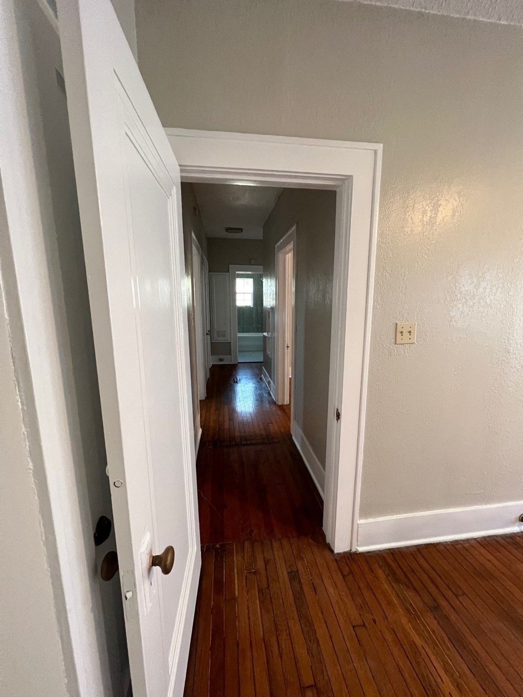 A hallway with a wooden floor and white walls.
