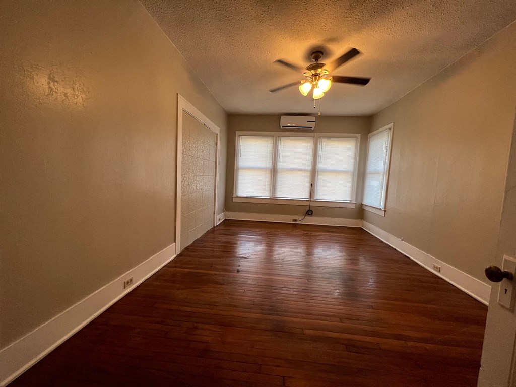 A room with a ceiling fan and wooden floors.