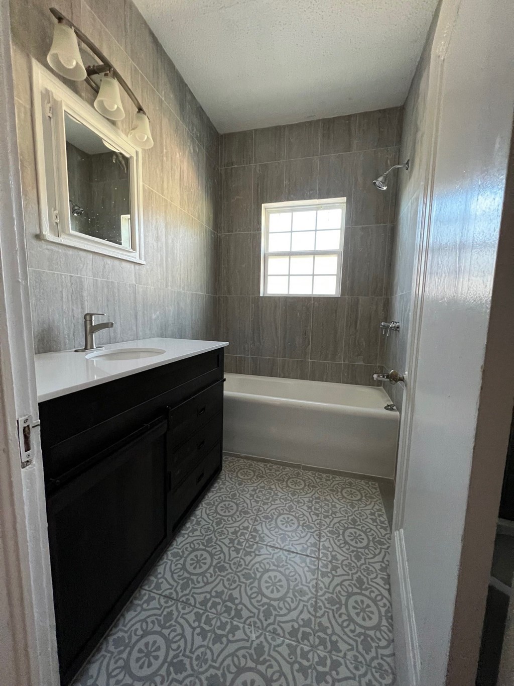 A bathroom with a patterned floor and a white sink.