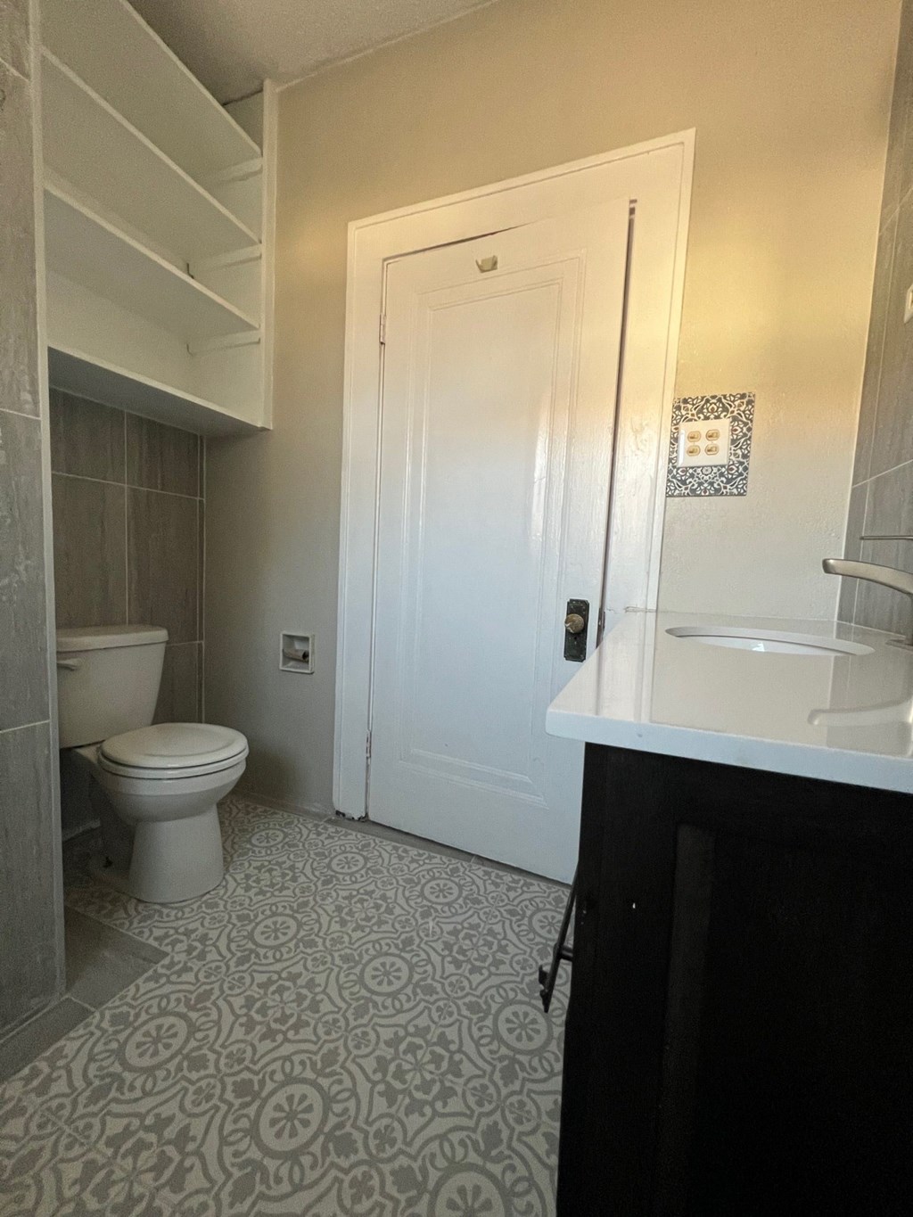 A bathroom with a toilet, sink, and a patterned floor.
